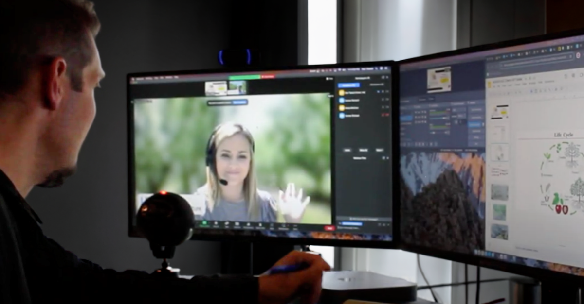 Virtual event producer at computer with multiple screens. Virtual event host with headset waving.